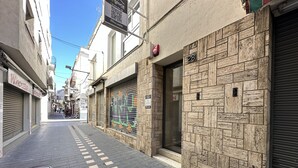 A narrow urban street with closed shops and a brick building facade. - AGI Gloria Rooms (Roses)