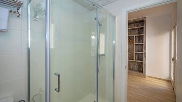 Un baño moderno con cabina de ducha de vidrio, inodoro y perchero para toallas.