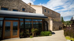 A stone building with large windows and a modern extension. - Hotel Mas Bosch 1526 (Avinyonet de Puigventos)