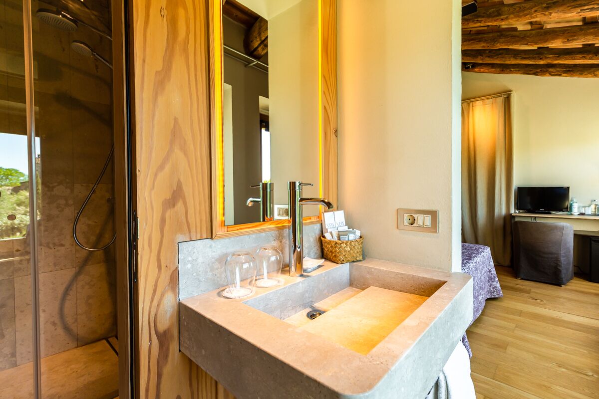 A modern bathroom with a large mirror, a granite sink, and a shower.