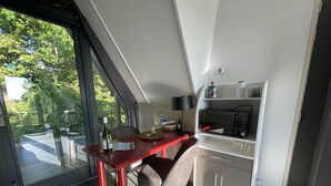 A modern kitchen with a dining area, featuring a red table, a microwave, and a cabinet. - Restinn Medemblik (Wieringerwerf)