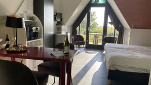 A hotel room with a bed, a desk with a lamp, a chair, a TV, and a balcony with a view. - Restinn Medemblik (Wieringerwerf)