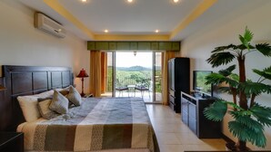Ein Schlafzimmer mit Bett, Fernseher, Pflanze und einem Balkon mit Aussicht.