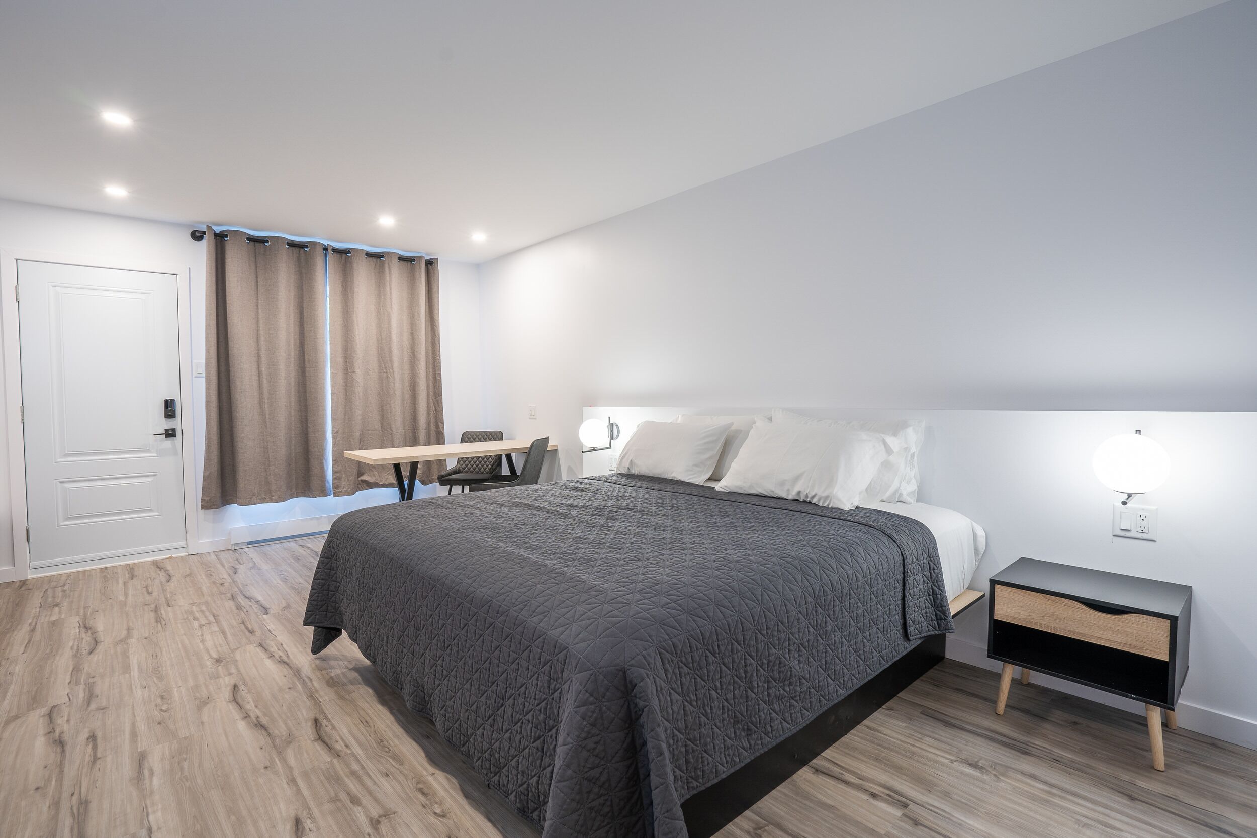 Een moderne slaapkamer met een bed, nachtkastje en bureau.