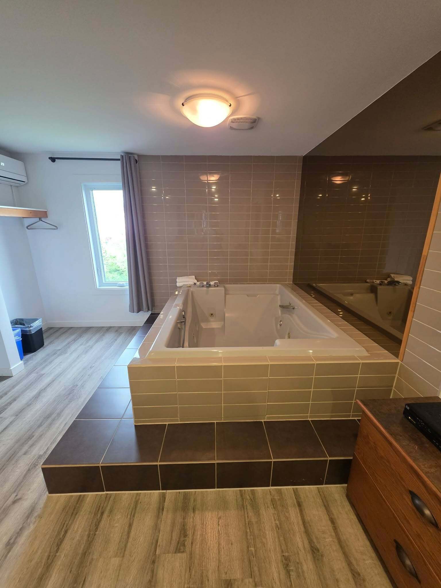 Une salle de bain moderne dotée d’une grande baignoire, d’un espace douche et d’un meuble-lavabo en bois.