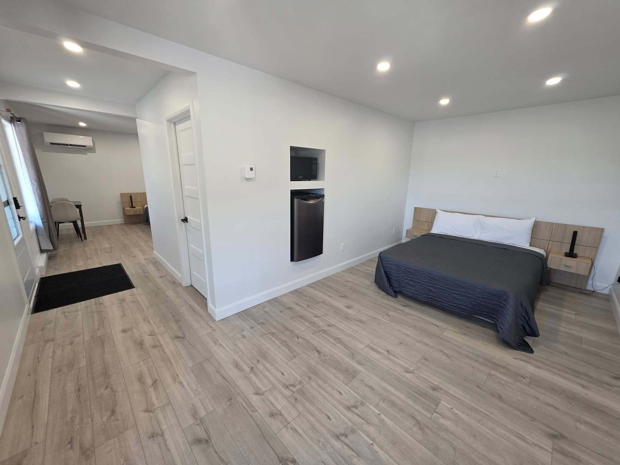 Une chambre à coucher comprenant un lit, une armoire intégrée, un four à micro-ondes et une porte donnant sur une autre pièce.