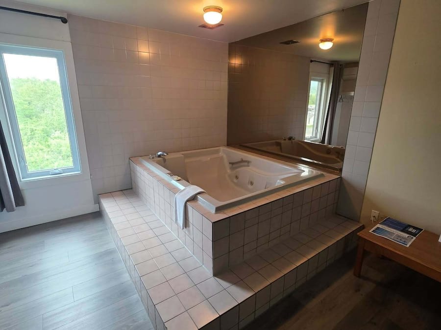 Een moderne badkamer met een ruime badkuip, een douchegedeelte en een raam voor natuurlijk licht.