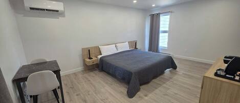 A modern bedroom with a bed, a desk, and a chair.