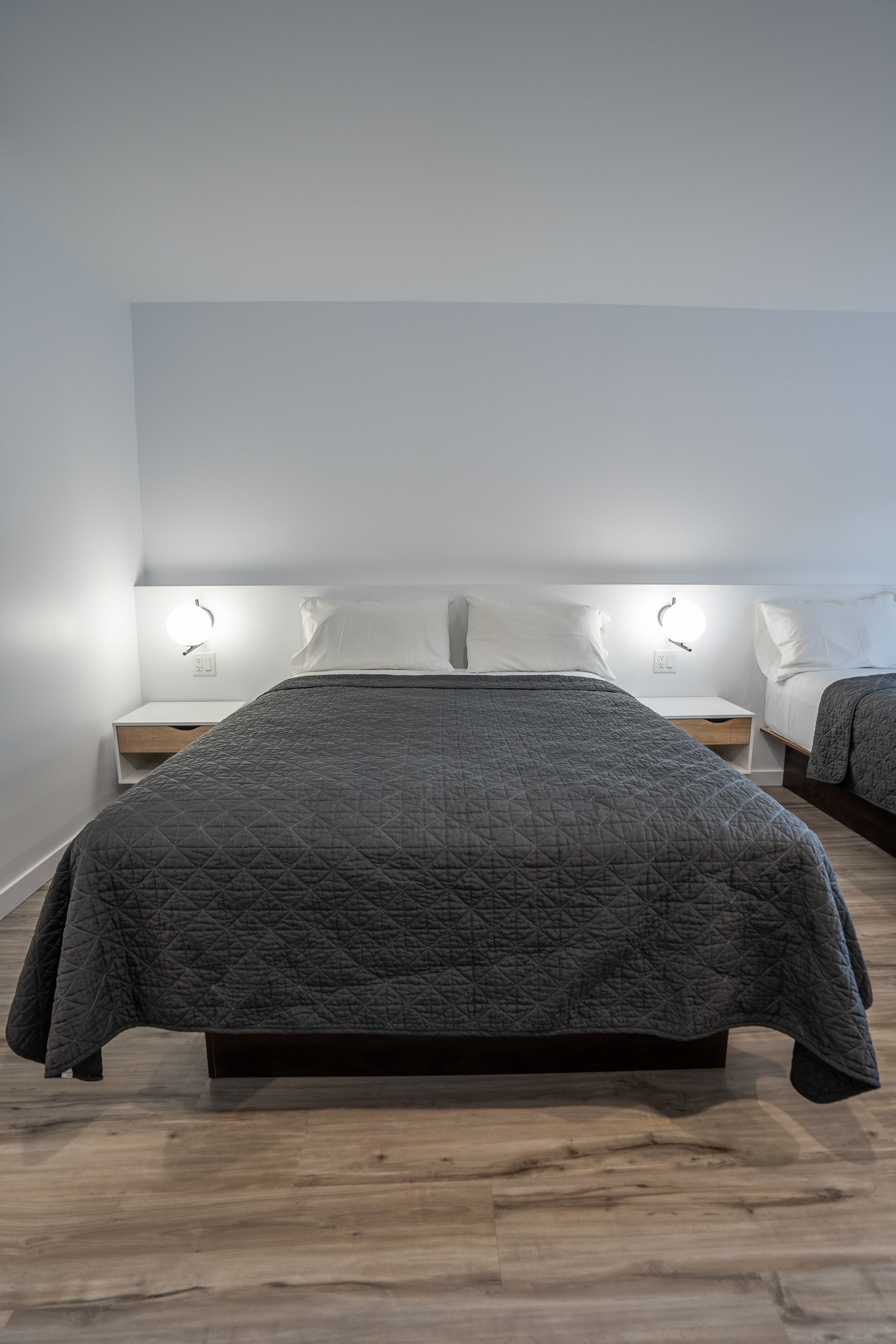 A modern bedroom with a large bed, bedside tables, and wall-mounted lighting.