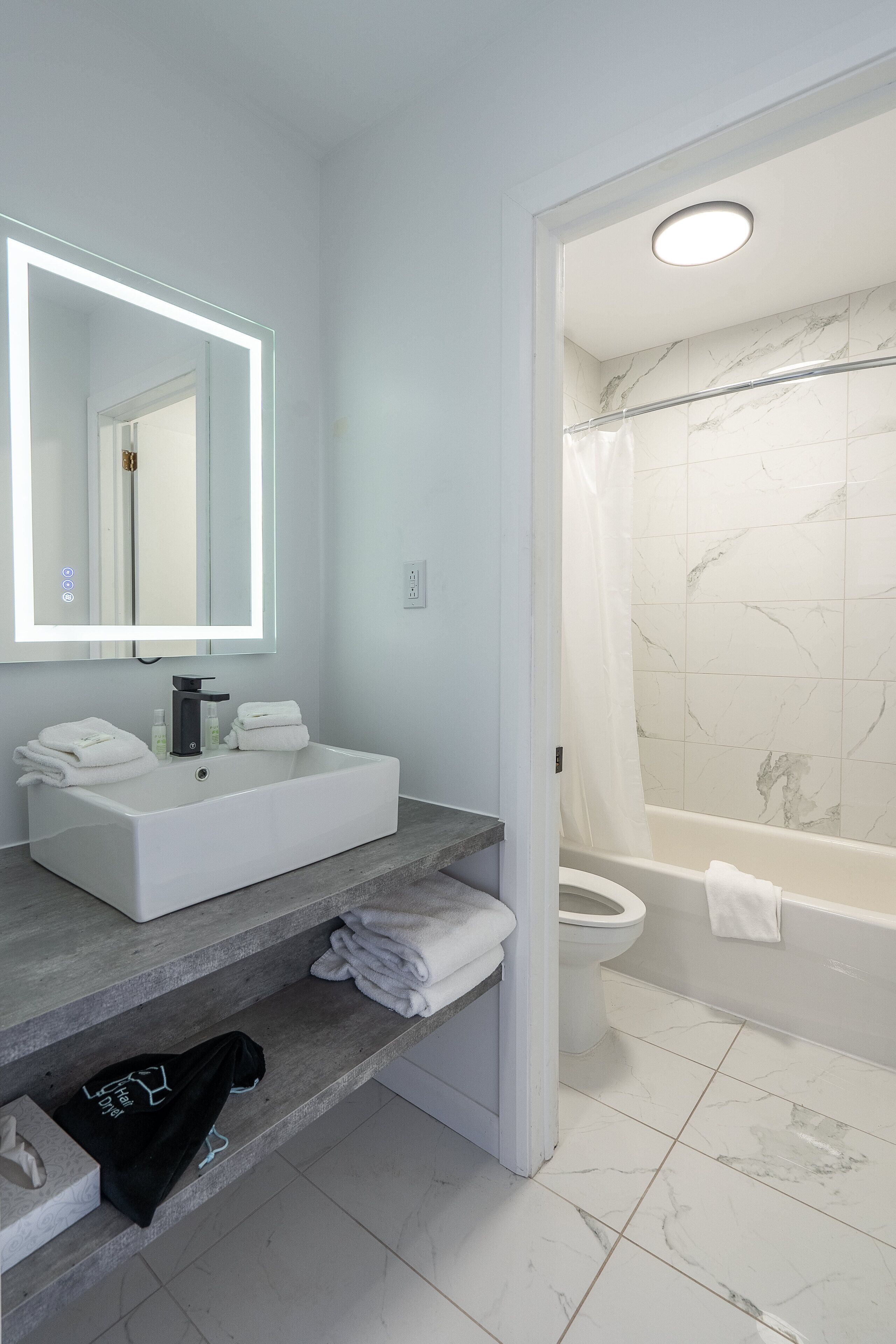 A modern bathroom with a white sink, mirror, and shower.