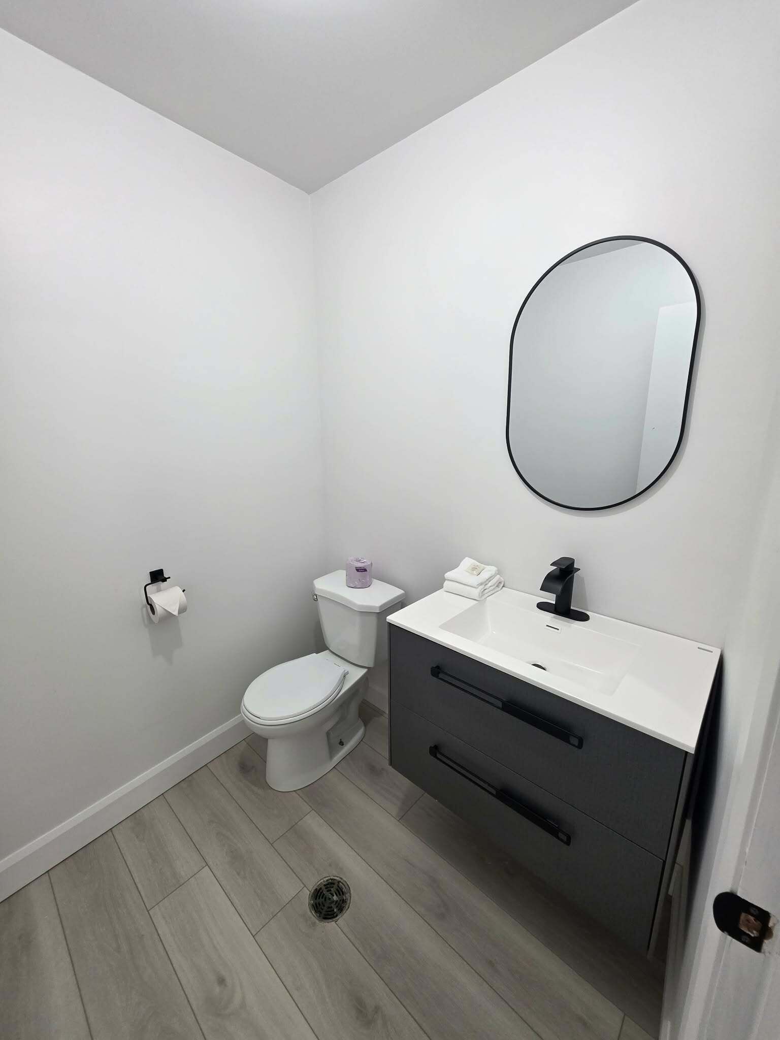 A small, modern bathroom with a toilet, sink, and mirror.