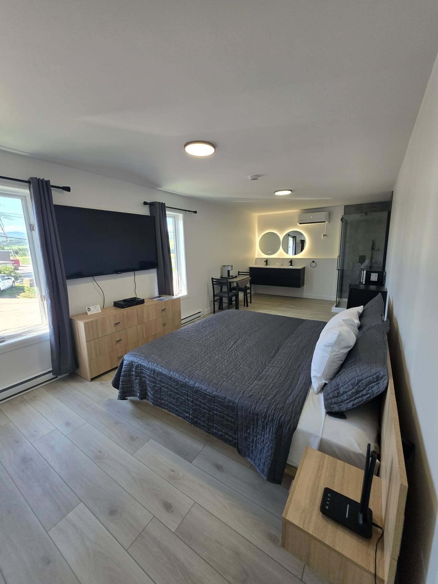 A modern bedroom with a large bed, bedside tables, a desk, and a TV.