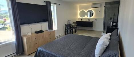 A modern bedroom with a large bed, bedside tables, a desk, and a TV.