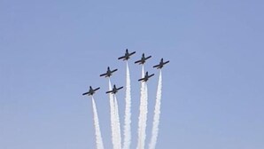 Un grupo de aviones a reacción realizando una maniobra aérea con estelas de humo sobre una masa de agua.