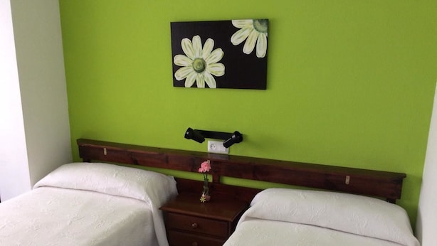 Habitación doble con dos camas, una mesita de noche con lámpara y una obra de arte en la pared.