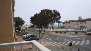 Vista de la calle con un paso de peatones, coches aparcados y un edificio que dice 'Academia General del Aire'.