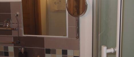 Un bagno con lavandino, specchio e porta doccia.