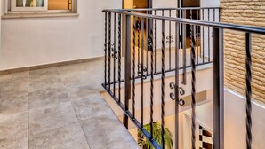 A modern interior with a staircase, multiple doors, and a balcony with a railing. - Hostel A2C - Adults Only (Seville)