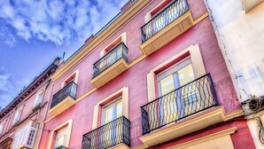 A multi-story building with balconies, a visible entrance, and a parking sign. - Hostel A2C - Adults Only (Seville)