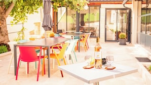 Eine Terrasse im Freien mit Tisch, Stühlen, einer Weinflasche und einem Glas.