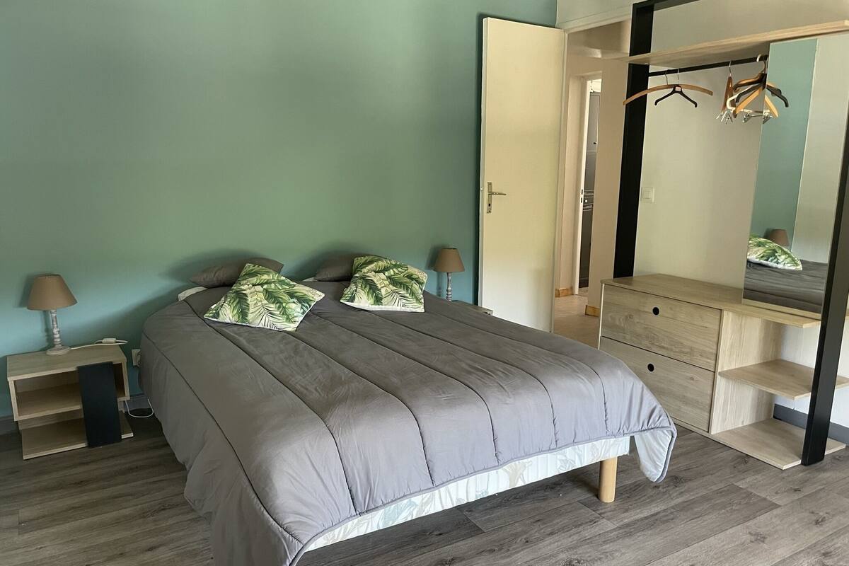 A bedroom with a bed, bedside tables, a dresser, and a mirror.