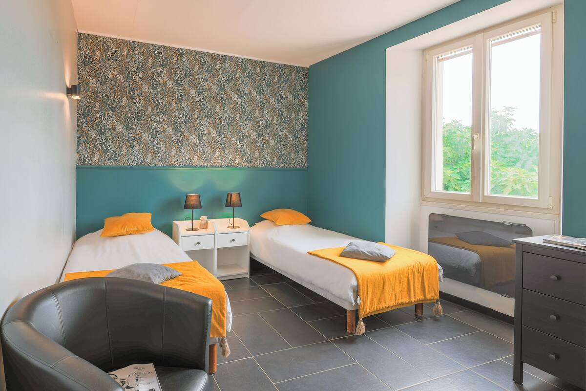 A modern bedroom with two beds, a desk, and a chair.