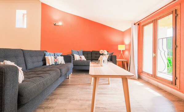 Una sala de estar con dos sofás grises oscuros, una mesa de centro de madera y una lámpara.