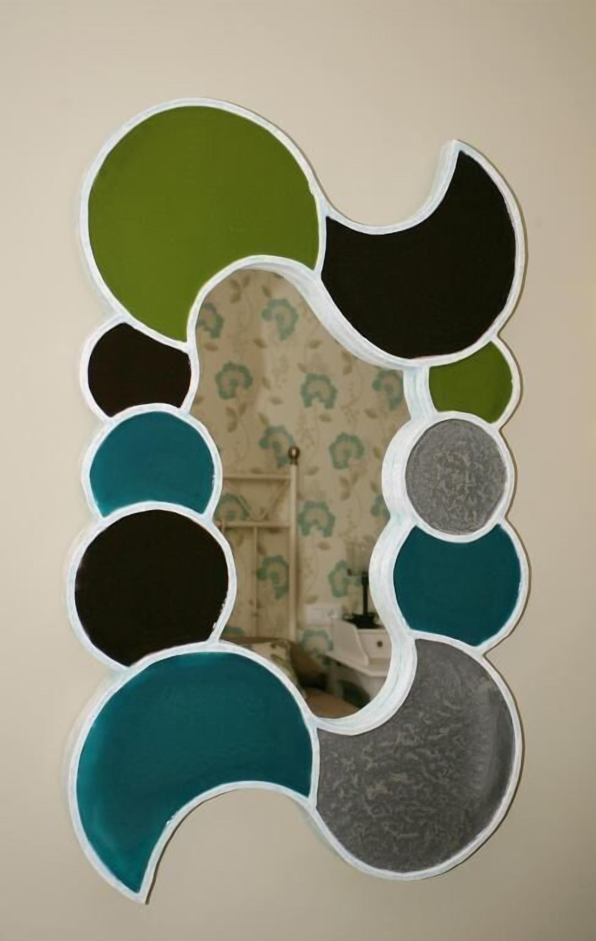 A wall-mounted mirror with a unique, abstract design featuring multiple circular segments in various colors.