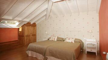A bedroom with a large bed, two bedside tables, and a wooden wardrobe.