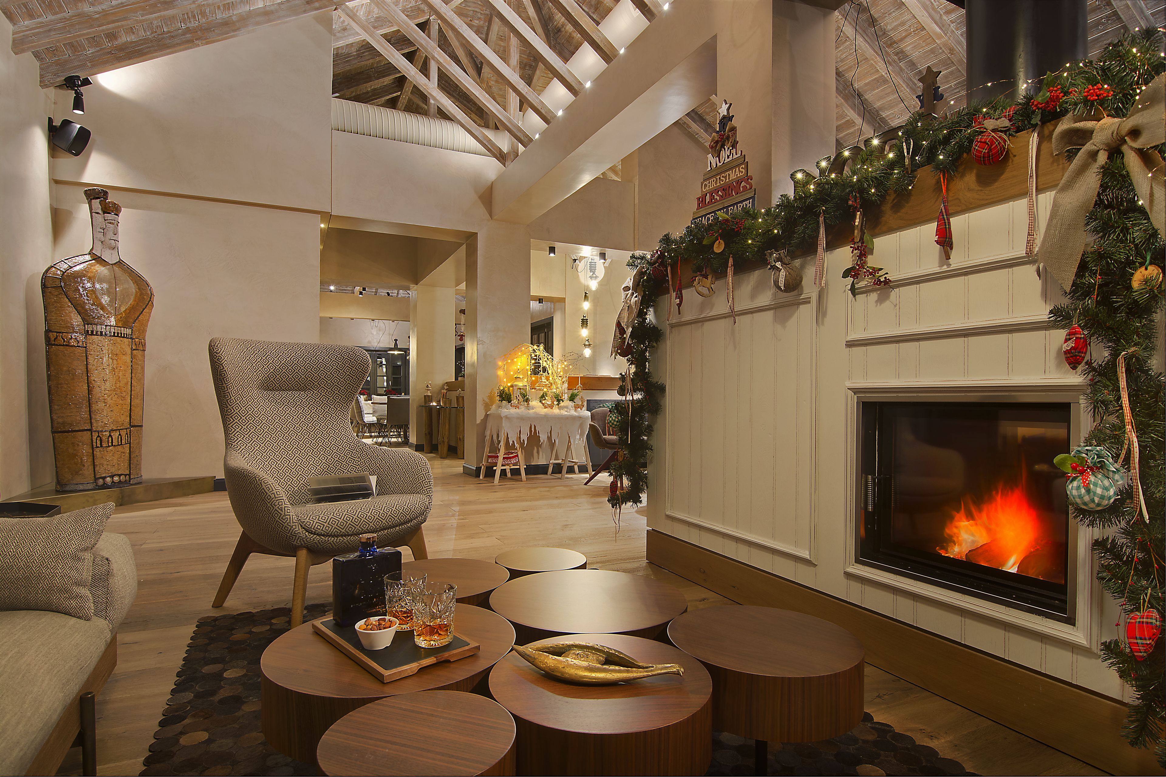 A cozy living room with a fireplace, wooden furniture, and festive Christmas decorations.