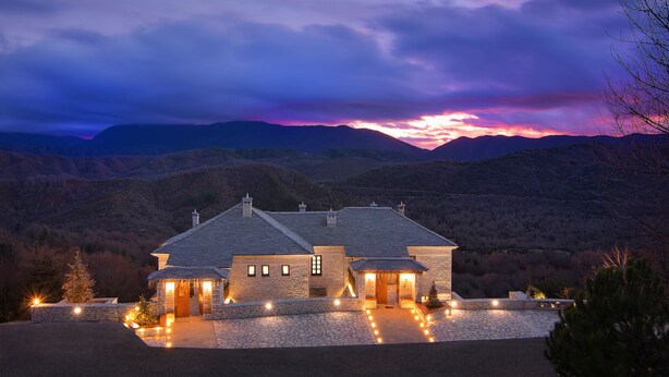 A stone house with a stone driveway, surrounded by mountains and a sunset sky. - Kores Boutique Hotel & Spa (Zagori)