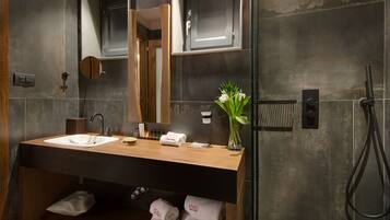 A modern bathroom with two sinks, a mirror, towel racks, and a shower area.
