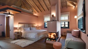 A cozy bedroom with a bed, bedside tables, a fireplace, and a seating area with a sofa. - Kores Boutique Hotel & Spa (Zagori)