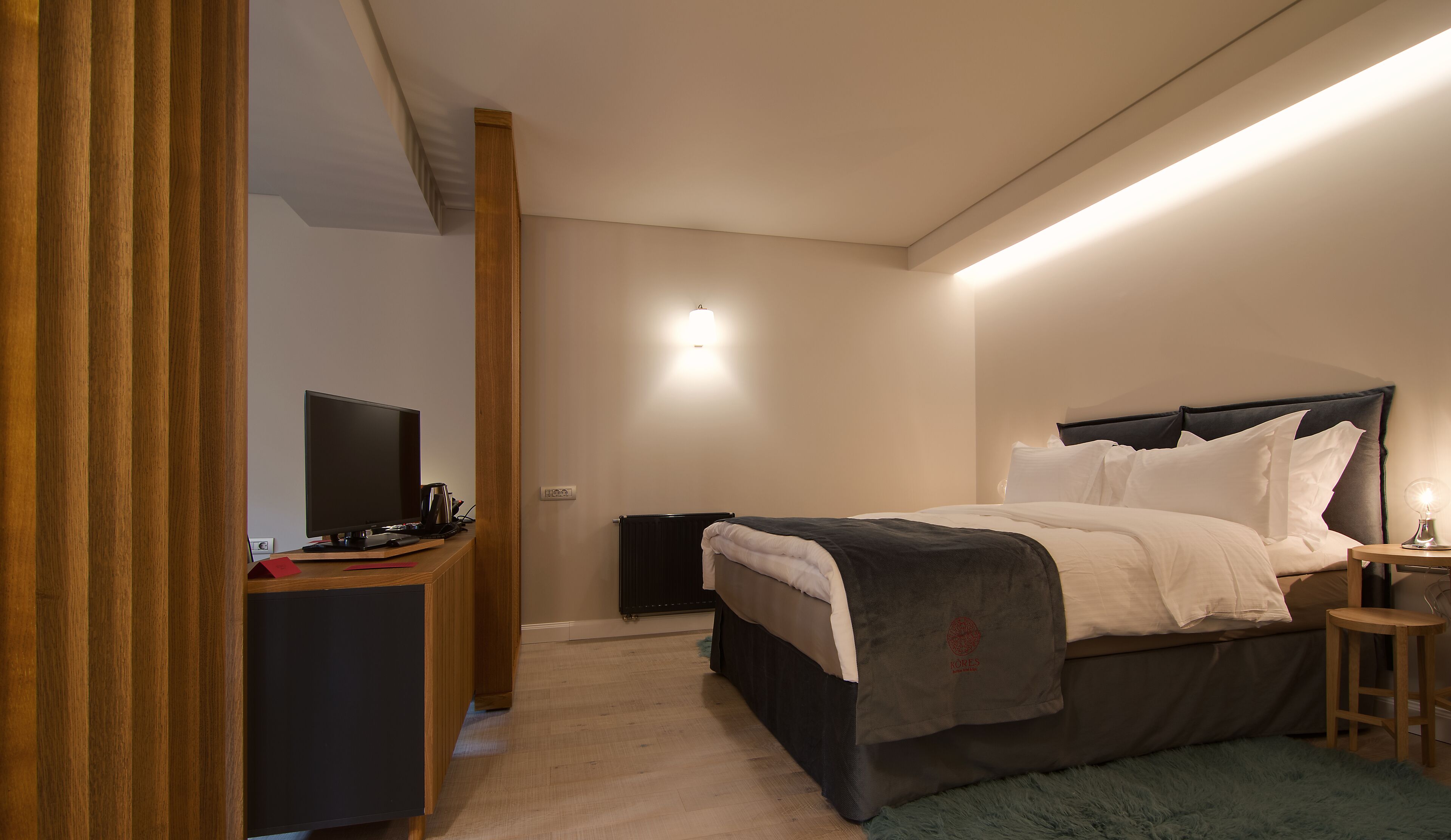Een moderne slaapkamer met een bed, nachtkastje en bureau met een computer.