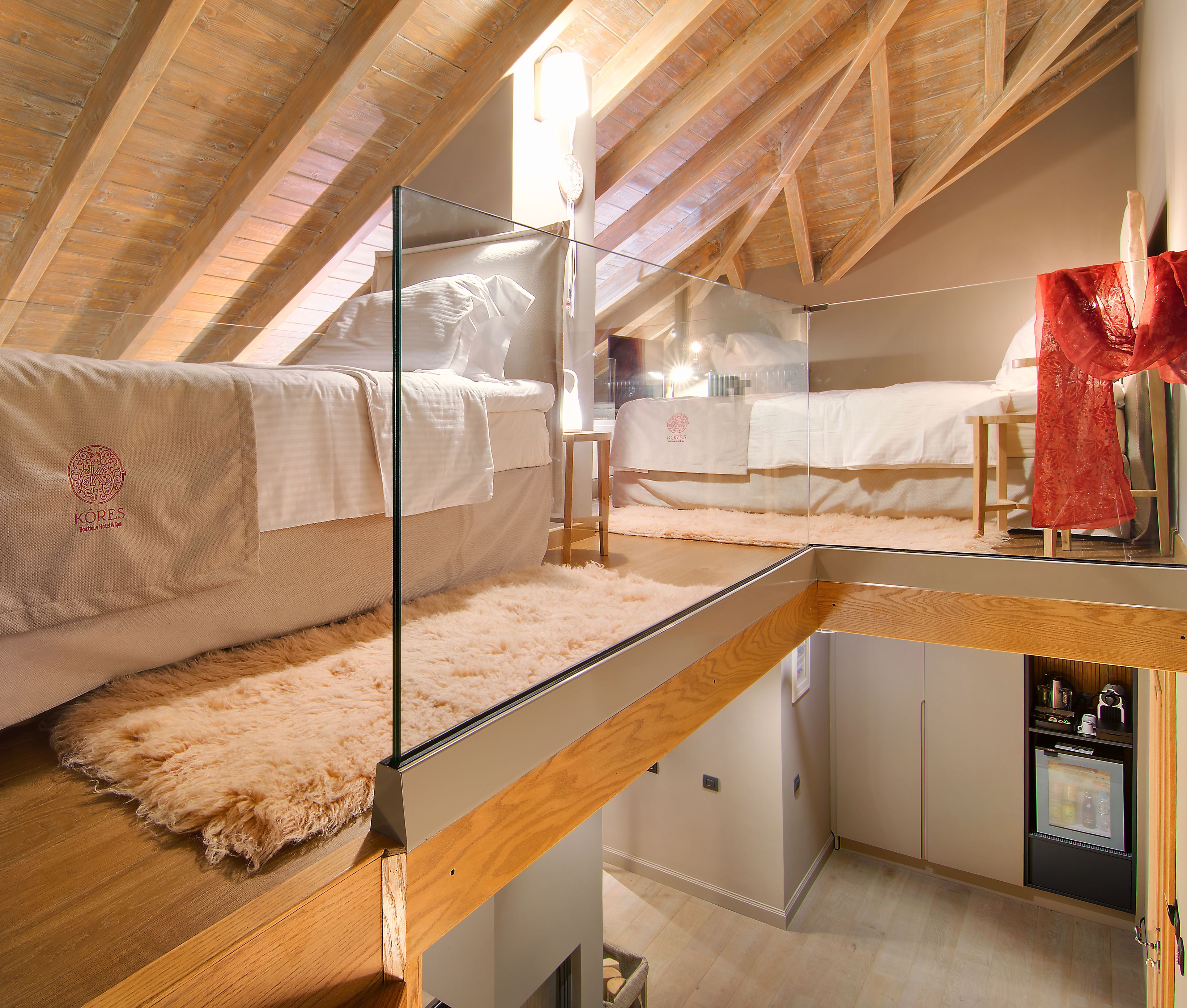 Een slaapkamer met een glazen wand, houten balken, een bed, een klein tafeltje en een kledingkast.