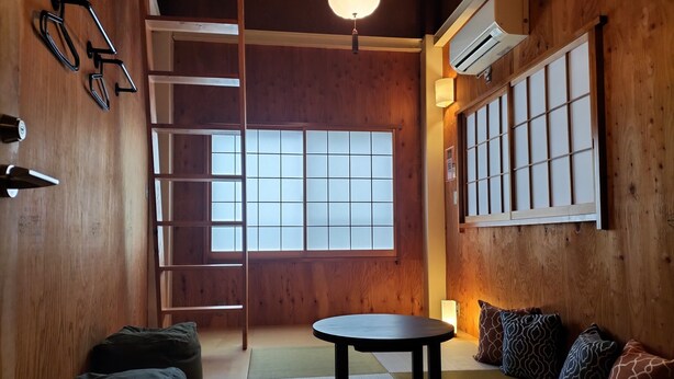 A traditional Japanese-style room with tatami flooring, a low table, cushions, a ladder, and sliding doors. - Vacation house Secretbase (Tokyo)