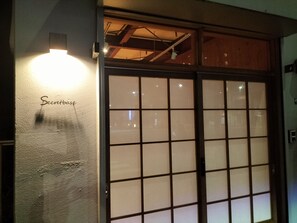 Una puerta corredera japonesa tradicional con un panel de vidrio satinado y una pequeña señal iluminada en la pared.