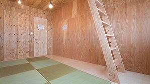 A room with wooden walls, a tatami mat floor, a wooden ladder, and two light fixtures. - Vacation house Secretbase (Tokyo)