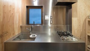 A modern kitchen with a stainless steel sink, a window, and a gas stove. - Vacation house Secretbase (Tokyo)