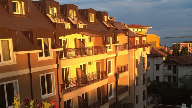 Un hôtel à plusieurs étages doté de balcons, d’une piscine et d’arrangements floraux.