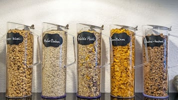 Five labeled containers of different cereal flakes.