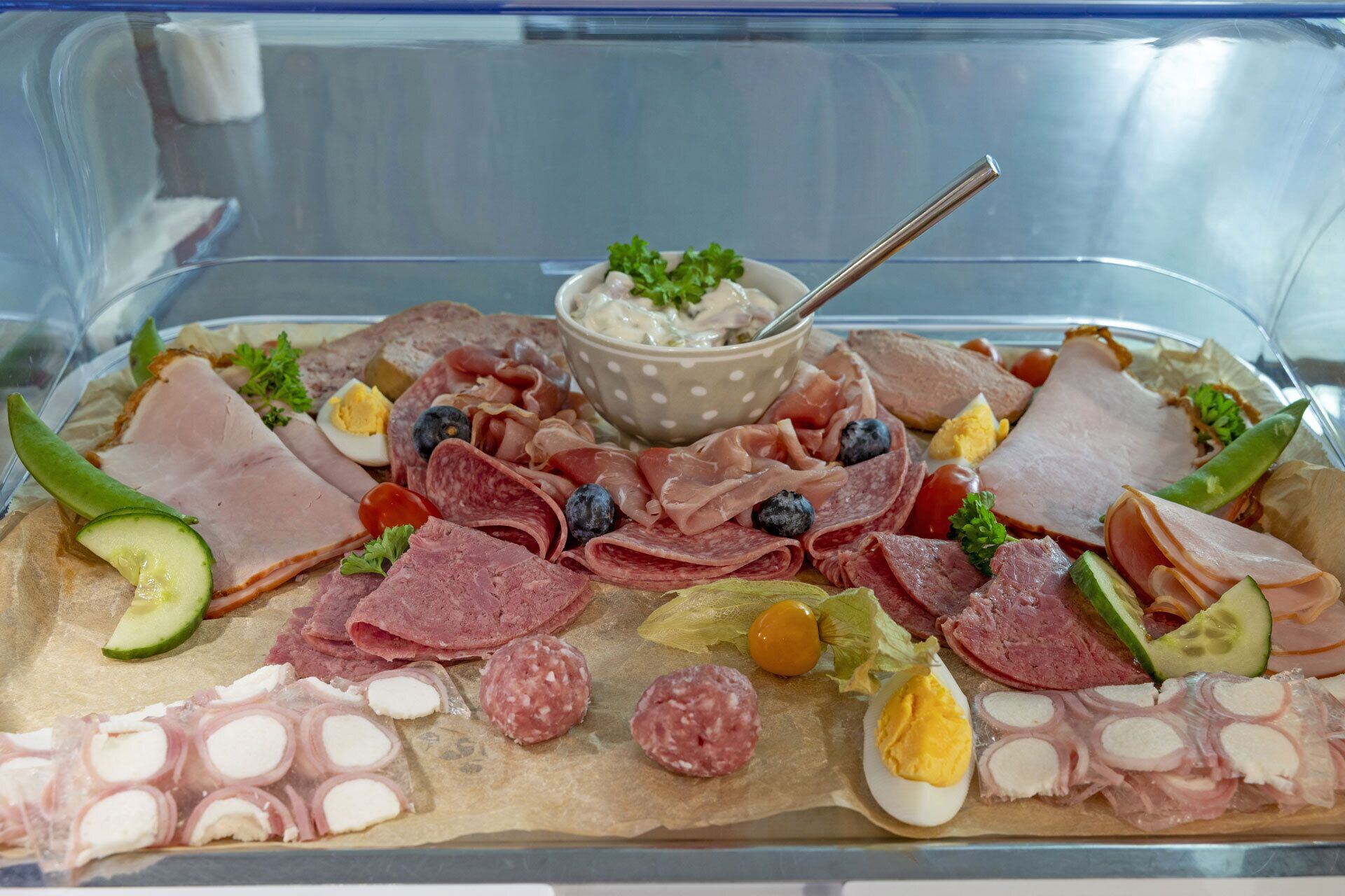 A charcuterie board with various meats, cheeses, and fruits.
