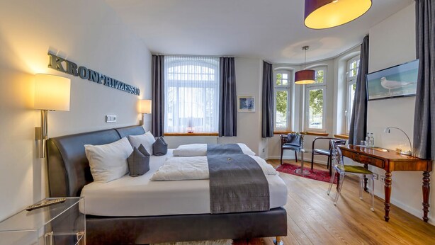 A modern hotel room with a large bed, a desk, and a TV.