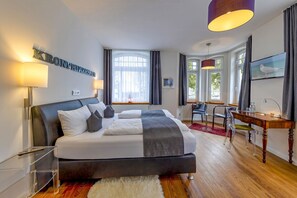 Una habitación de hotel moderna con una cama grande, un escritorio y un televisor.