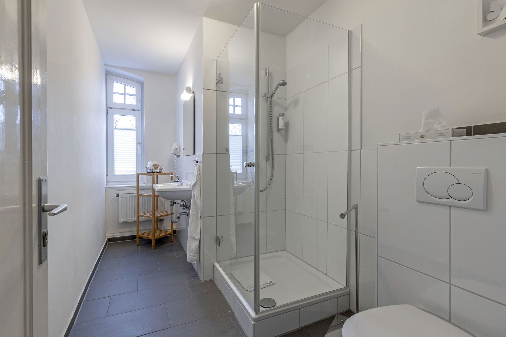 A modern bathroom with a glass-enclosed shower, a white sink, and a toilet.