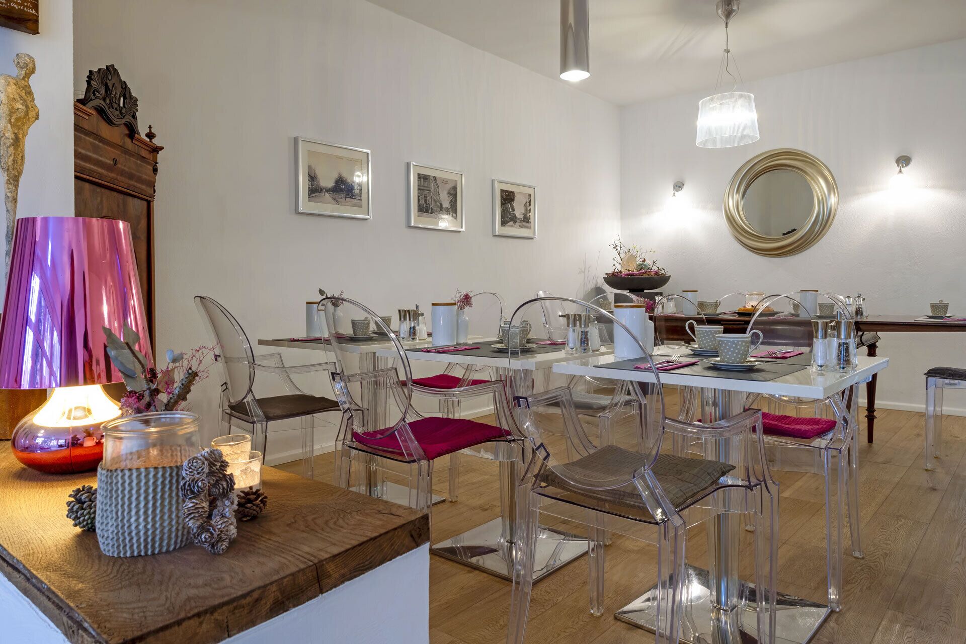 Un comedor moderno con sillas transparentes, una mesa de madera y una araña.