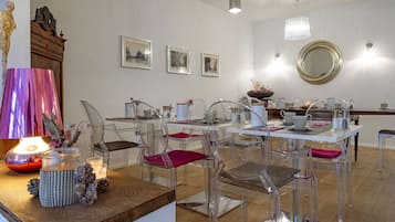 Un comedor moderno con sillas transparentes, una mesa de madera y una araña.