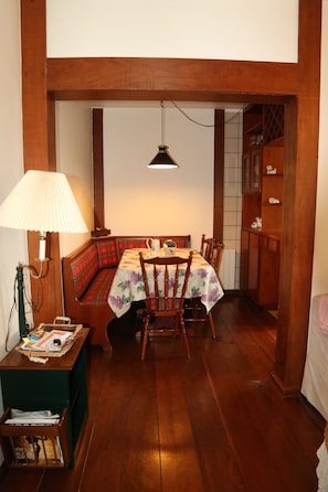 A dining area with a wooden table, chairs, a bench, and a lamp.