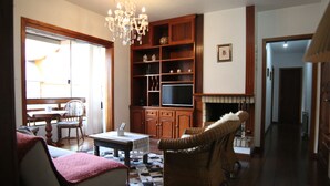 Un salon doté d’une cheminée, de meubles en bois et d’un lustre.