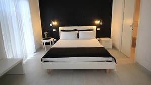 Une chambre moderne avec un grand lit, des tables de chevet et un mur d’accent de couleur noire.